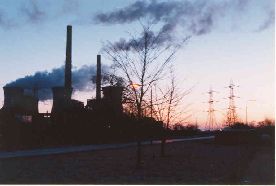 The power station is in the distance with the glow of the sun just about to rise behind it