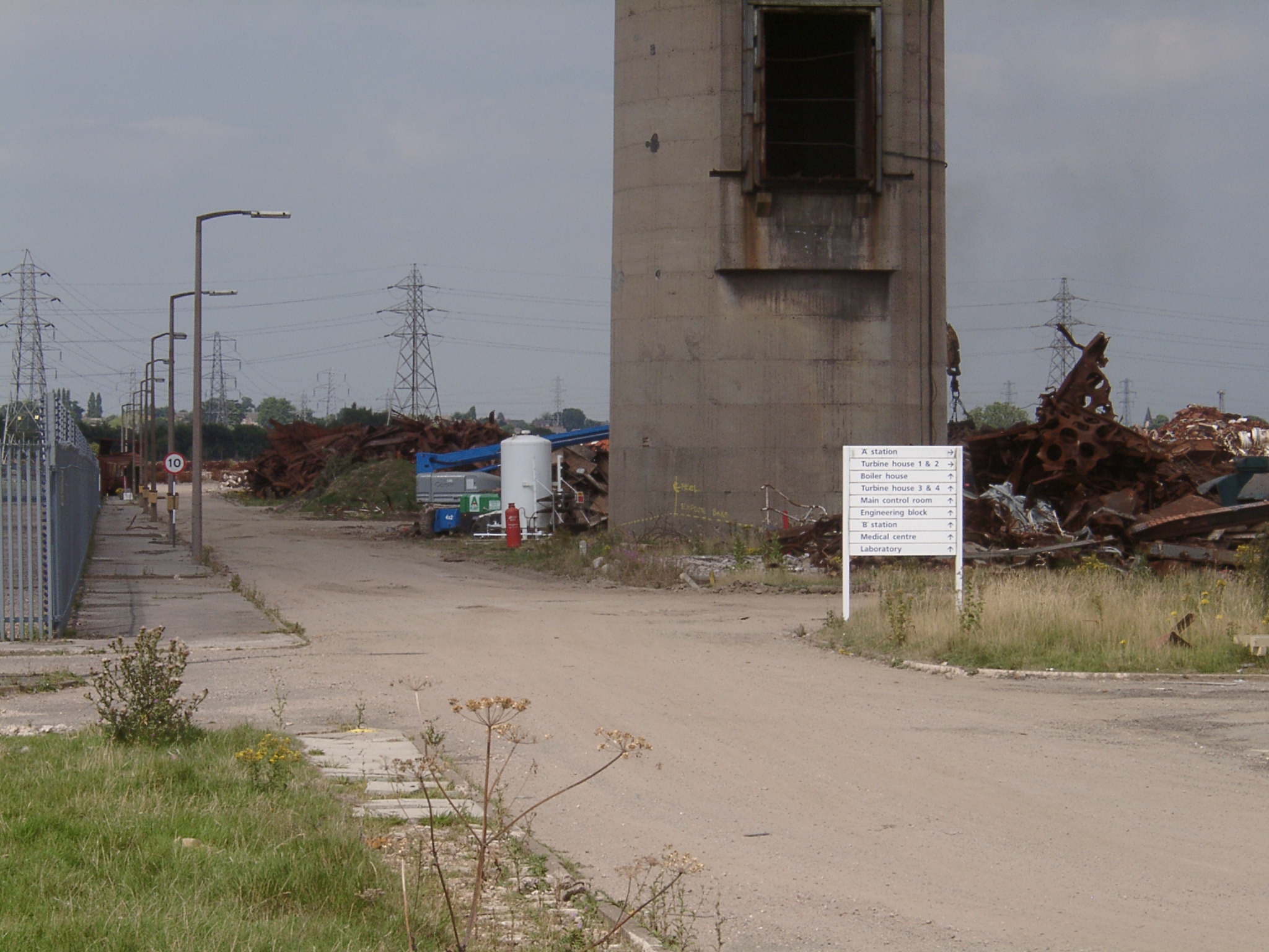 Scrap piled high against a redundnat chimney at Willington Power Station